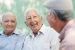 Three gentlemen sitting outside talking and smiling